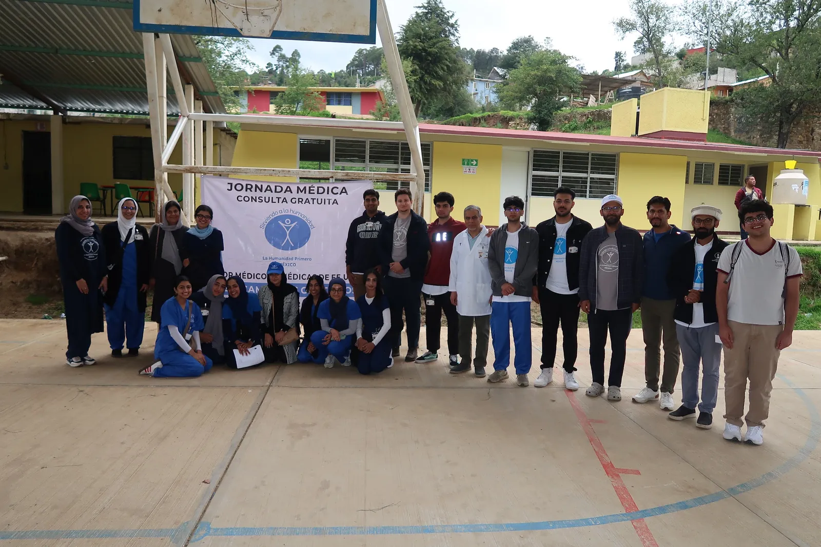 Loyola University Chicago students, physicians, and mission leaders stand on the clinic court beneath a Jornada Médica banner in Mexico