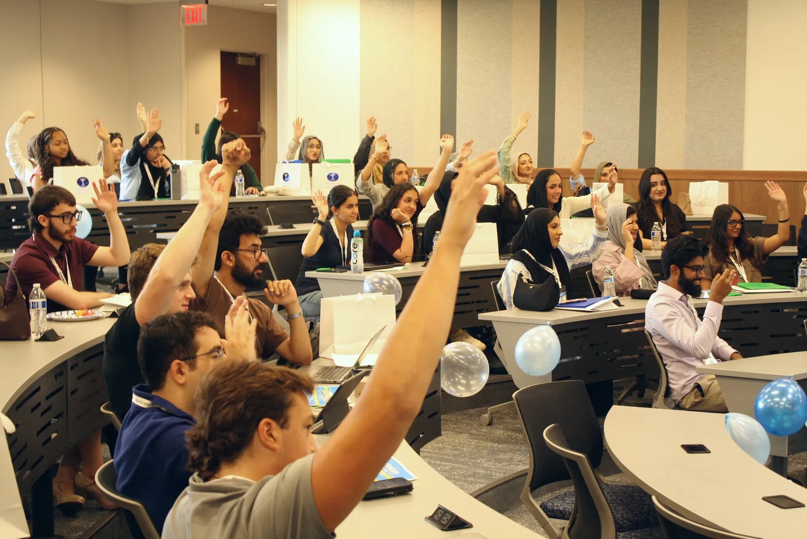 Delegates raise their hands to answer a question in a lecture hall at the 2025 Leadership Summit
