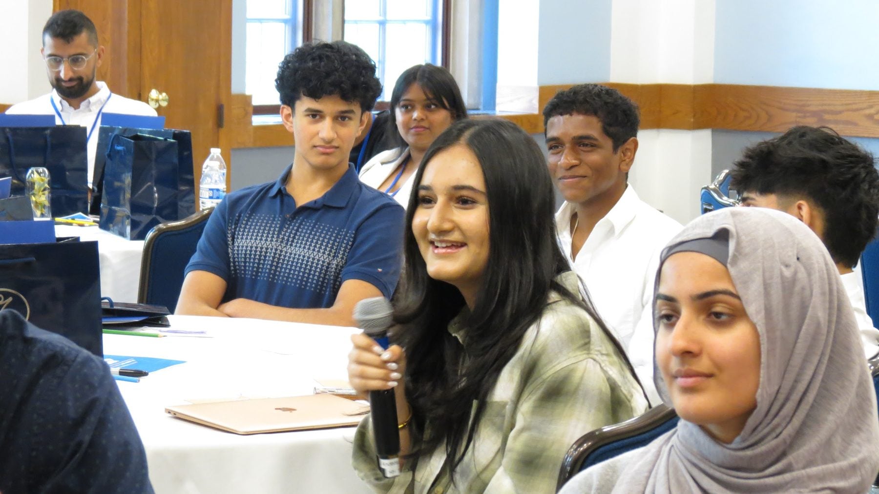 A chapter delegate holds a microphone and smiles during an open discussion at Summit 2024