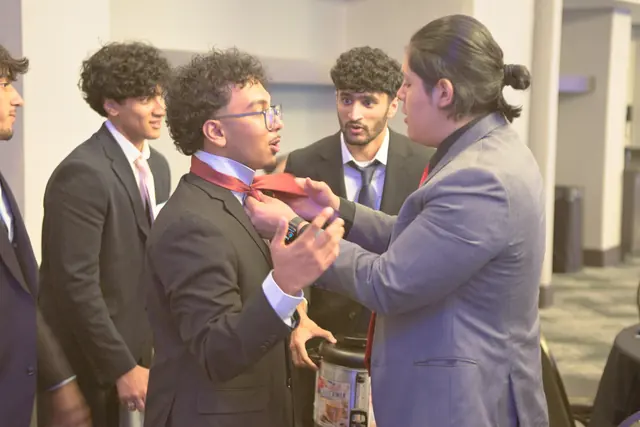 Students in suits help a friend adjust his tie before the evening begins at the Gift of Health Gala 2026.