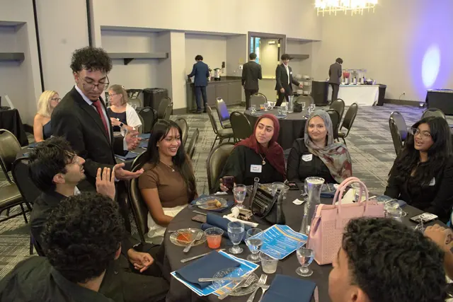 Students and guests talk and laugh around a round banquet table at the Gift of Health Gala 2026.