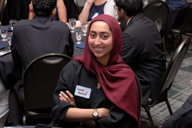 A smiling student wearing a name tag sits at a banquet table at the Gift of Health Gala 2026.