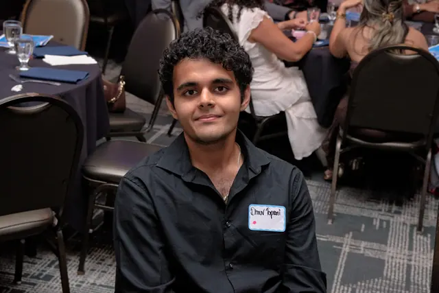 A young man wearing a name tag smiles from his seat at the banquet at the Gift of Health Gala 2026.