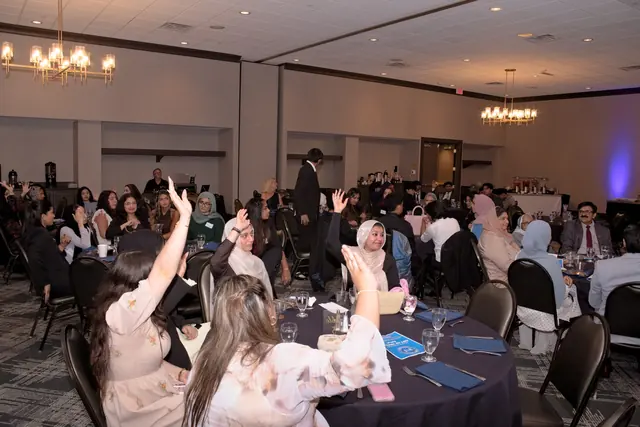 Guests across the Gift of Health Gala ballroom raise their hands during the pledge drive