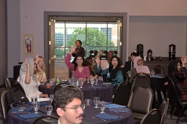 Guests at the Gift of Health Gala banquet tables wave toward the camera