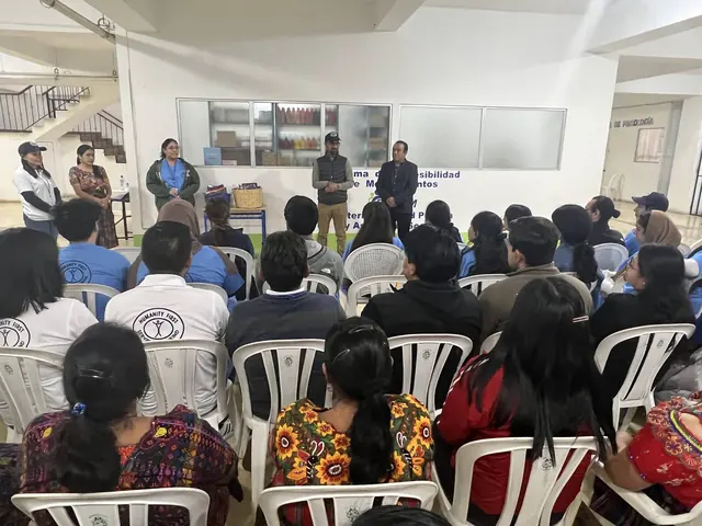 Community members and volunteers sit in rows of white chairs facing speakers at a Ministry of Health facility during the Guatemala mission.