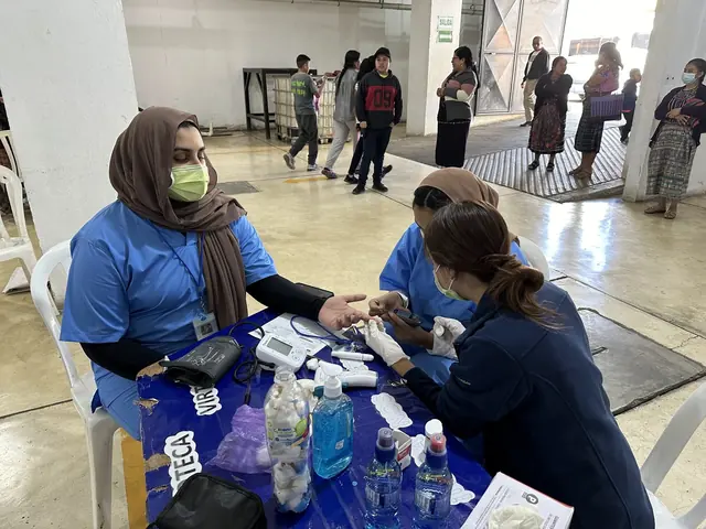 A student volunteer takes a woman's blood pressure at the registration table