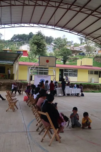 Patients sit in rows of wooden folding chairs under a covered basketball court converted into a free medical clinic in Mexico.