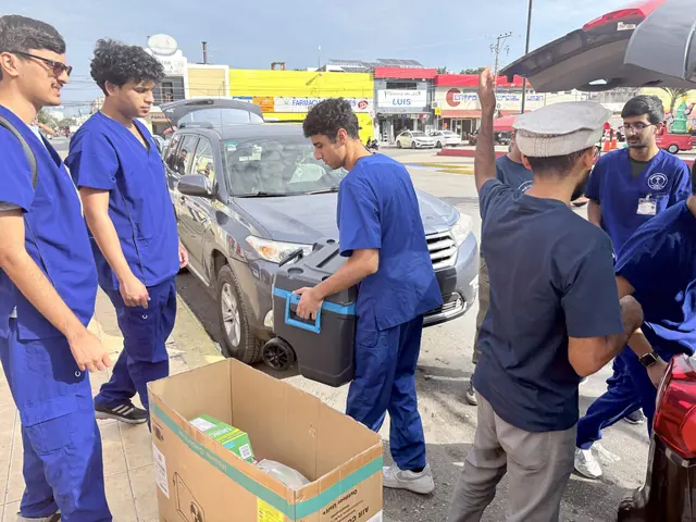 Students in blue scrubs unload a cooler and boxes of supplies from a car at the Gift of Health mission in Mexico.