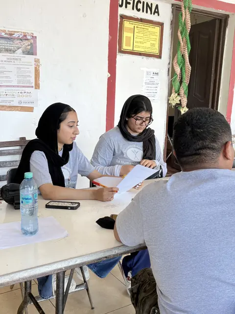 Two volunteers take notes while speaking with a patient at the registration desk at the Gift of Health mission in Mexico.