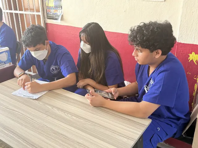 Two student volunteers take notes while a patient describes her symptoms