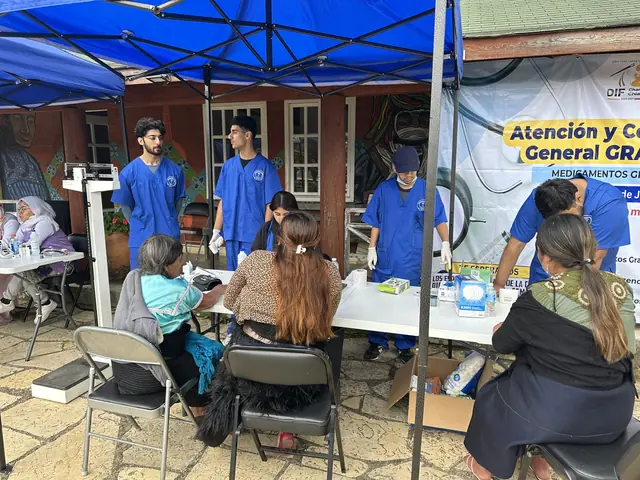 Patients wait under a blue clinic tent while student volunteers work the registration tables