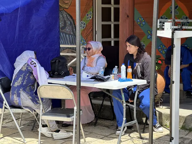 A volunteer and a colleague speak with a patient at a shaded registration table at the VCU Gift of Health mission in Mexico.
