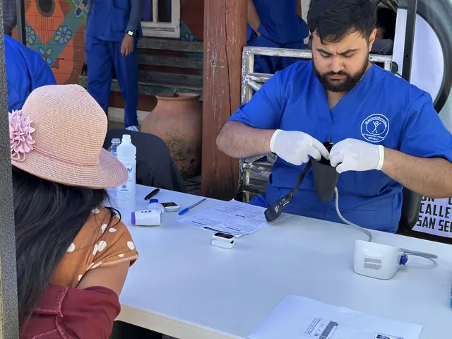 A gloved student volunteer runs a fingerstick glucose test