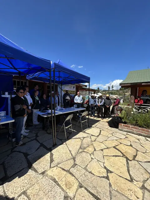 Blue canopies shelter screening tables and waiting community members on a sunny stone plaza at the VCU Gift of Health mission in Mexico.