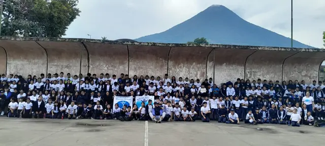 Hundreds of students gather for a whole school photo with a volcano rising behind the campus at the Masroor Ahmad School in Guatemala.