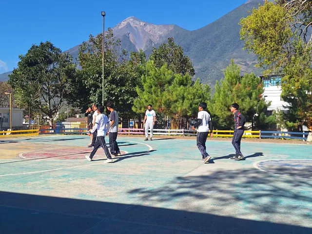 Students run a play on the school court with a volcano in the background at the Masroor Ahmad School in Guatemala.