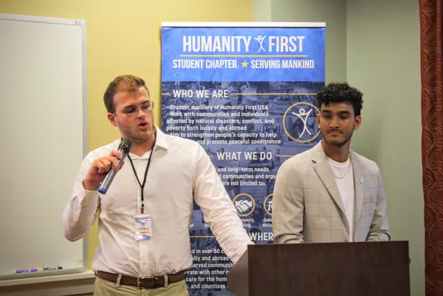 A presenter speaks into a microphone beside a co-presenter at the podium during a session at the HFSD Leadership Summit '23.