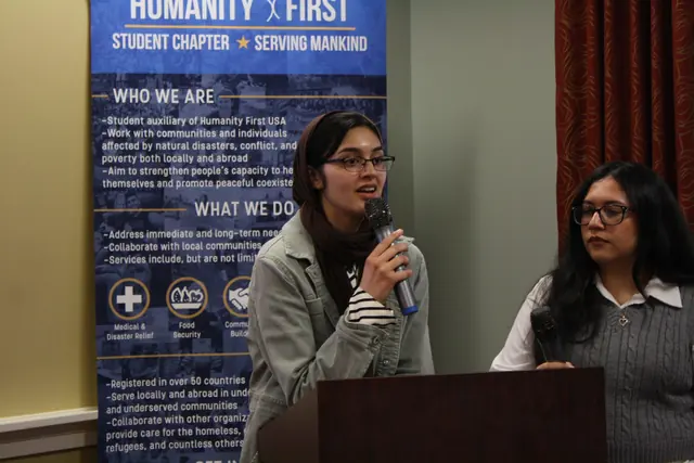 A student leader speaks into a microphone alongside fellow panelists in front of a Humanity First banner at the HFSD Leadership Summit '23.