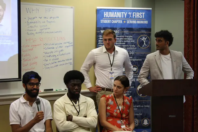 Students seated at the front answer questions with a microphone as presenters listen beside a whiteboard at the HFSD Leadership Summit '23.