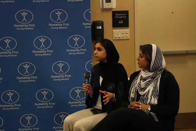 Two student panelists sit together and speak before a Humanity First backdrop during a discussion at the HFSD Leadership Summit '23.