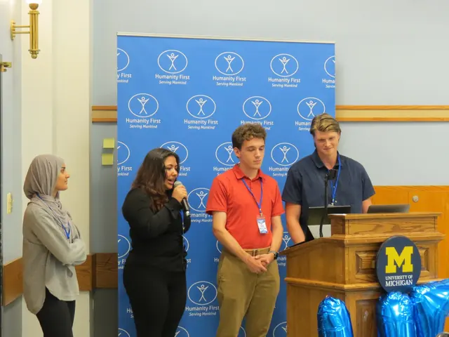 A student speaks into a microphone while her teammates stand beside her