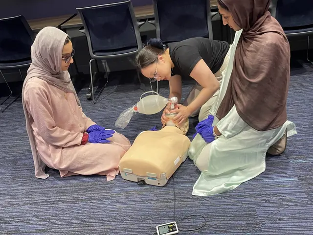 Two delegates practice rescue breaths on CPR manikins