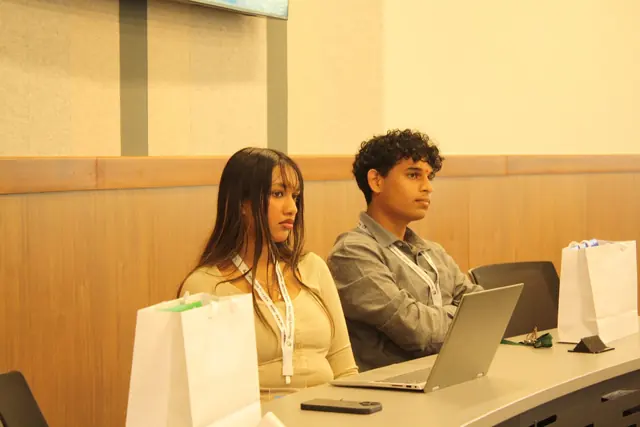 Two delegates listen during a session with laptops open