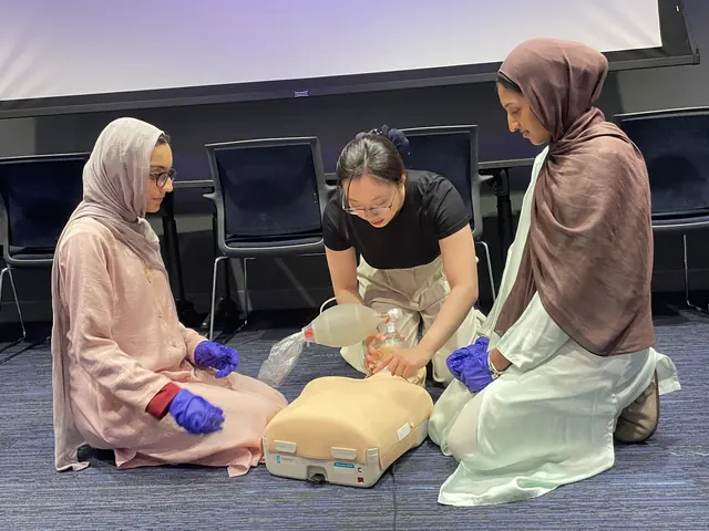 Students in gloves practice rescue breathing with a bag valve mask on a CPR manikin at the 2025 Leadership Summit.