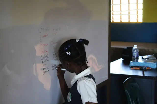 A young student solves a problem on the whiteboard