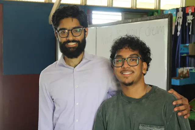 Two volunteers smile together in the classroom