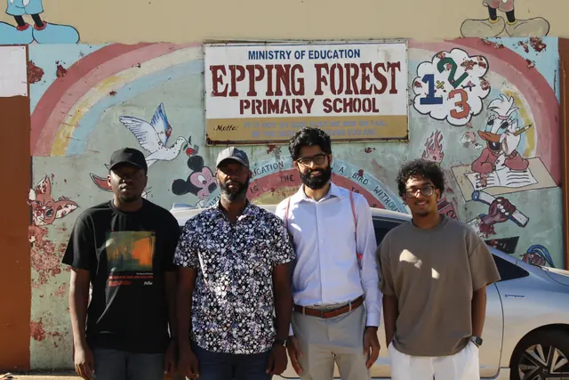 Four volunteers stand in front of the Epping Forest Primary School sign